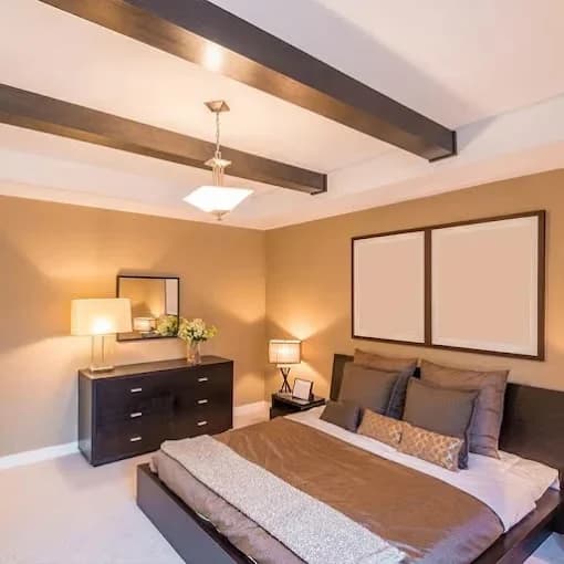 Painting work by Nashville Painting Company - Brentwood in Brentwood, Tennessee. The image shows a tan bedroom with dark ceiling beams.