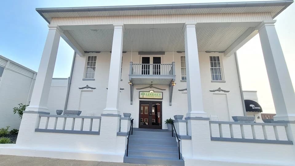 This is an image from Hernandez Painting, located in Tennessee. The exterior photo shows a large white two-story commercial building with tall columns and a freshly painted façade.