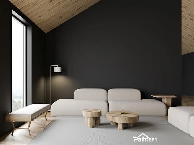 This is an image from Painter1 of Tulsa, located in Oklahoma. The image shows a modern living room with dark painted walls, light wood ceiling panels, minimalist white seating, and natural wood accent tables.