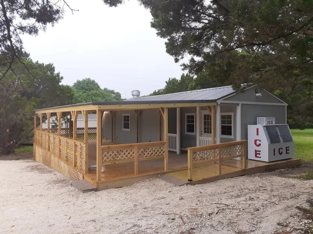 "This is an image from James Painting & Remodeling, located in Texas. The image shows a gray exterior building with a large newly constructed wooden wraparound deck and an outdoor ice freezer."