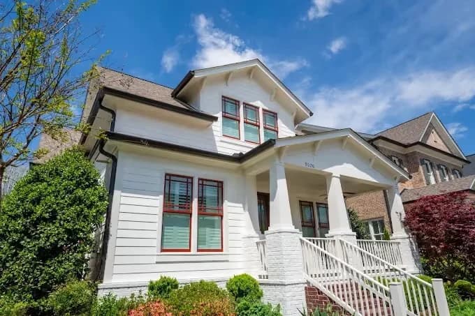 Exterior painting by AllBright Pro Painting in Smyrna, Tennessee. The image shows a white two-story home with a front porch and red window trim.