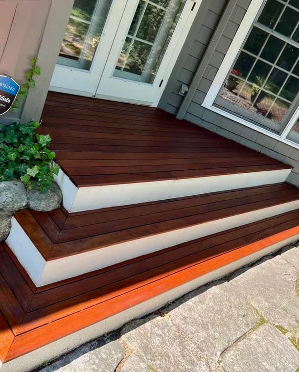 This is an image from Right Track Painting & Sealcoating, showing newly refinished wooden steps leading up to a home entrance. The rich brown stain contrasts with the white trim, giving a polished and durable appearance.