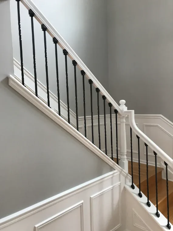 A staircase with white trim and black railings painted by Jordan's Painting LLC. The work highlights a clean, modern finish.