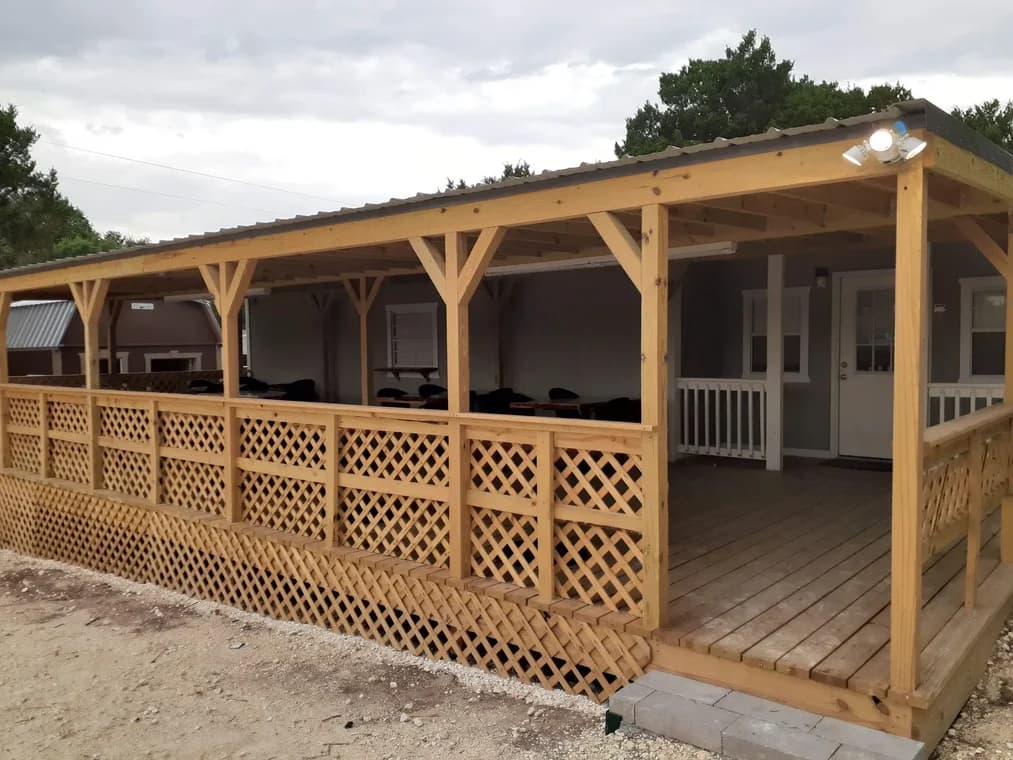 "This is an image from James Painting & Remodeling, located in Texas. The photo shows a covered wooden deck structure with lattice skirting and exposed beams."