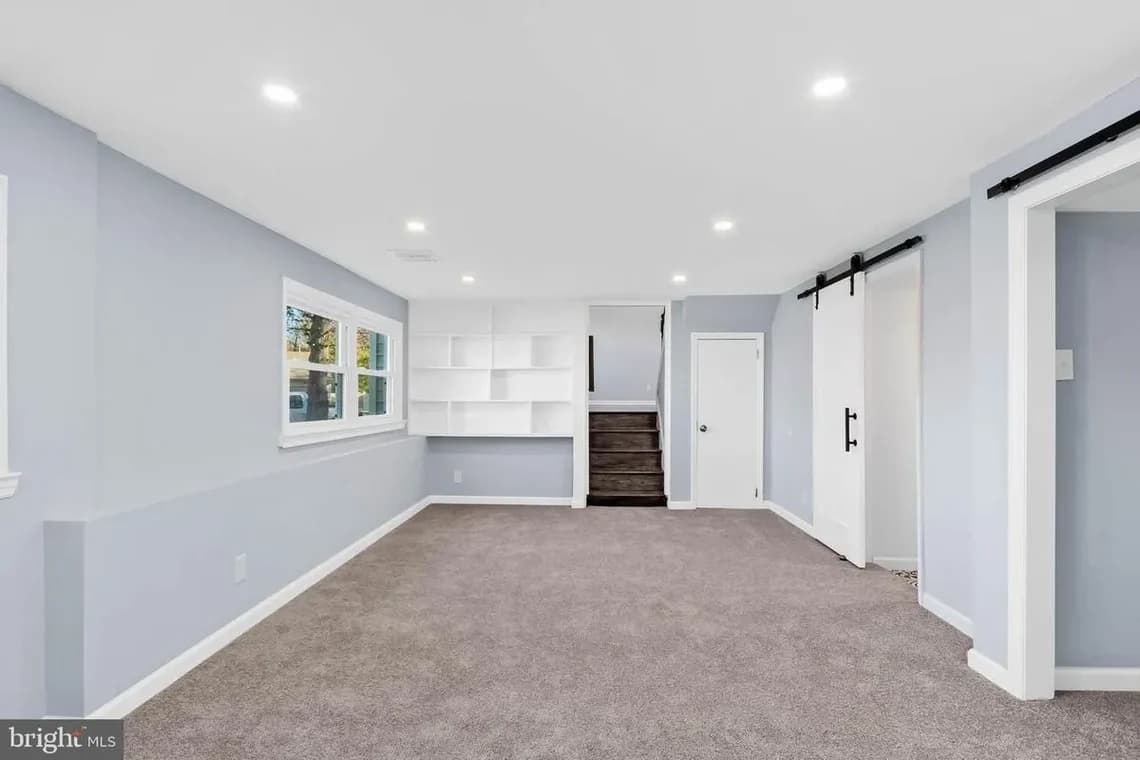 A modern kitchen painted in light gray with white cabinetry, stainless steel appliances, and a subway tile backsplash.