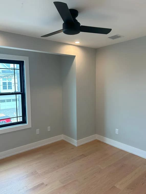 This is an image from Carfagno Professional Painting & Power Washing LLC. It features a modern interior room with smooth gray walls, white trim, and wood flooring.