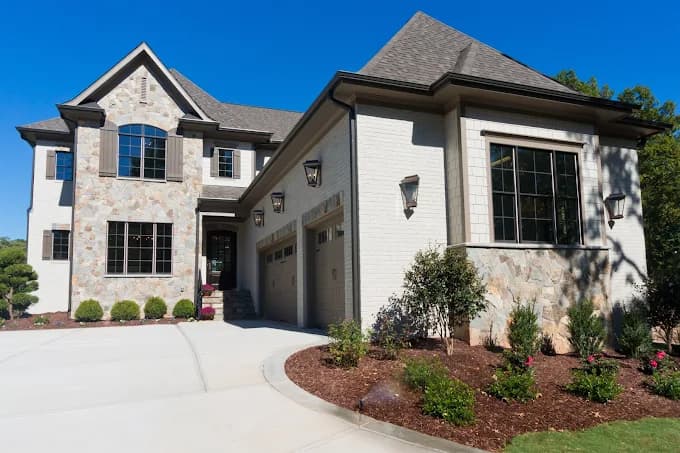 This is an image from VS Pro Painting, located in Texas. The exterior photo shows a large two-story home with light brick, stone accents, and newly painted trim in a clean, modern color scheme.