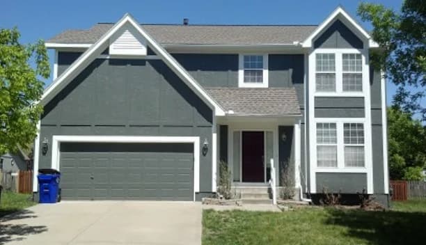 This is an image from CertaPro Painters of Shawnee Mission, KS. The image is a two-story gray home in Shawnee Mission KS with fresh exterior paint and white trim.
