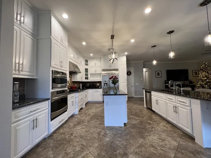 This is an image from Spray-Net Lexington, located in Kentucky. The image shows a professionally painted kitchen interior with white cabinetry, recessed lighting, and a clean, modern island layout.
