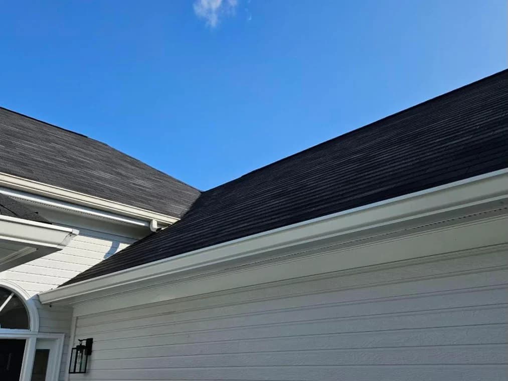 This is an image from Goodpaster Painting & Guttering, located in Tennessee. The image is a close-up view of roofline and gutters on a freshly painted white home by Goodpaster Painting & Guttering.