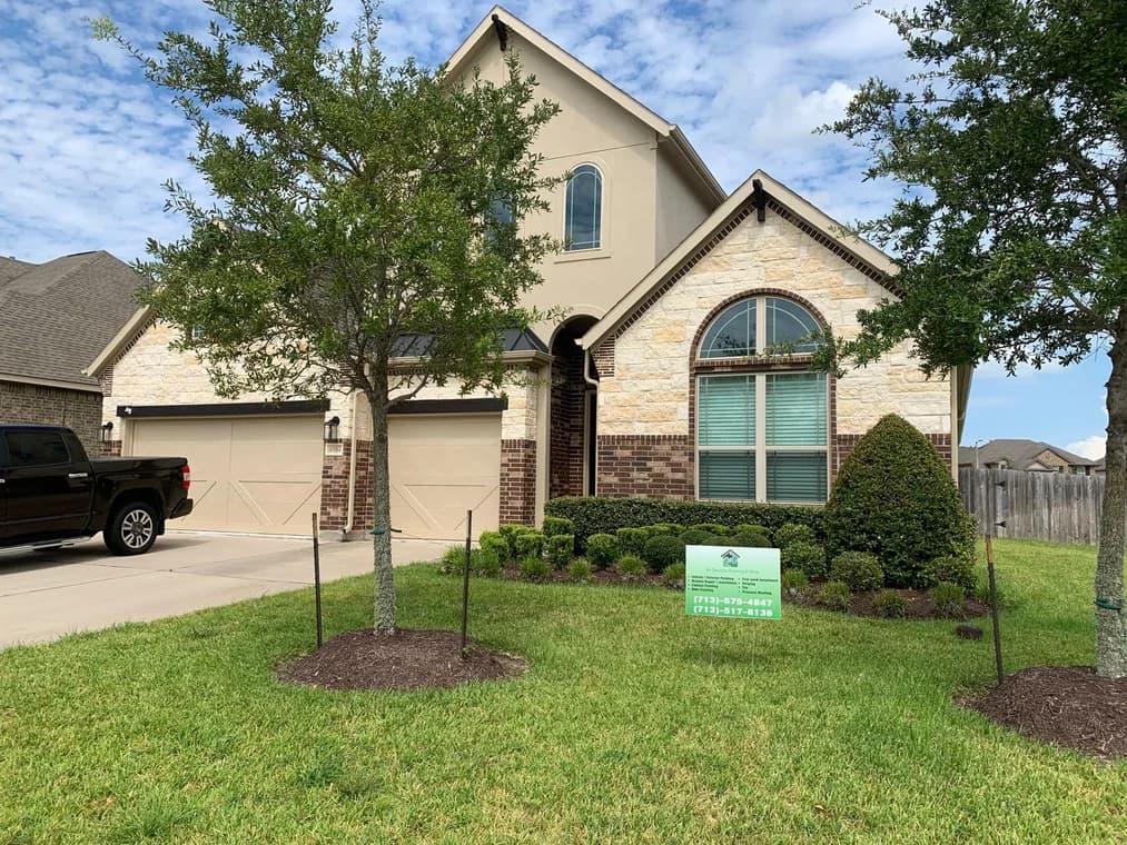 "This is an image from All Seasons Painting LLC, located in Texas. The exterior photo shows a two-story brick and stone home with beige garage doors, landscaped shrubs, and a contractor yard sign in the front lawn."