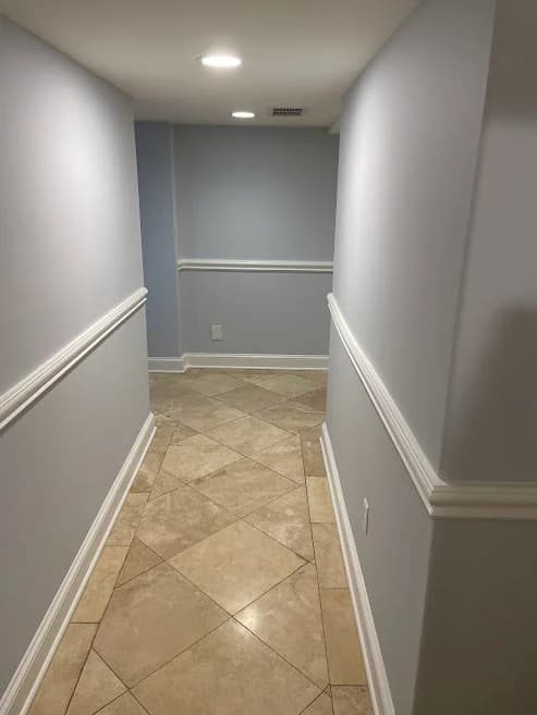 Hallway painted by Brush Masters Painting Contractors LLC in Egg Harbor Township, New Jersey, with soft gray-blue walls, tile floors, and white trim.