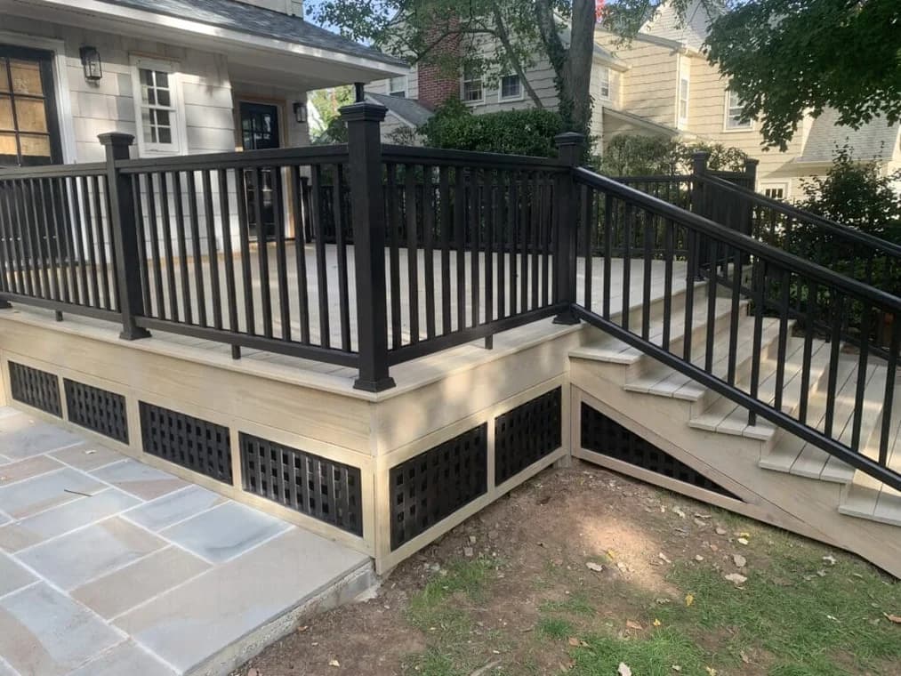 This is an image from Hoffman Interior Painting, located in Michigan. The image shows a newly finished outdoor deck with light wood flooring, black railings, and matching stairs highlighting professional deck painting, railing finishing, and exterior wood coating services.