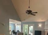 Interior painting project by Aztec Painting Inc. in Wilmington, NC. The image shows white walls and trim, a ceiling fan, dark flooring, and patio doors.