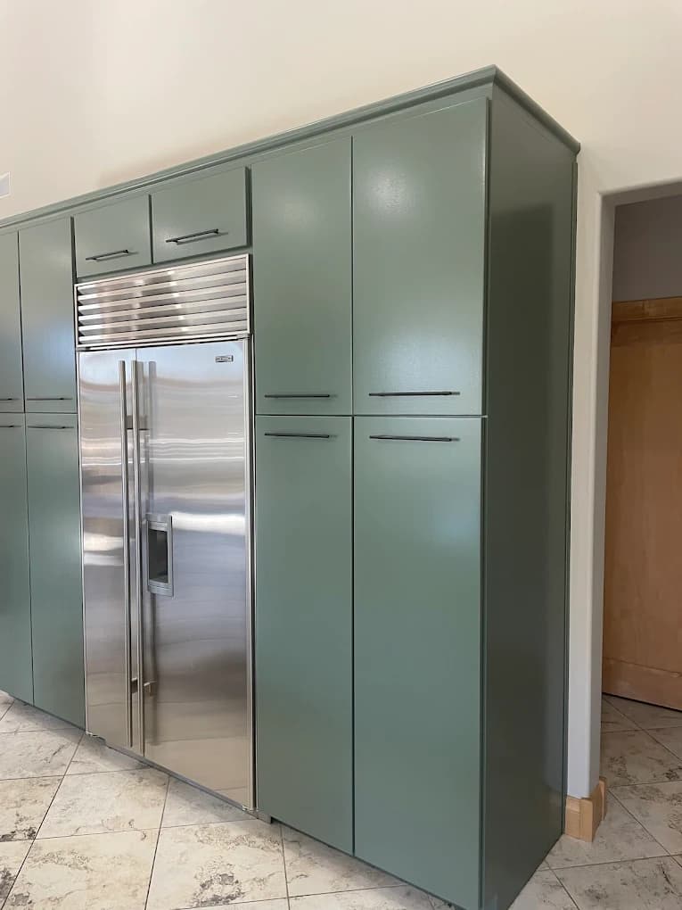 Cabinet painting project by Michael's Painting Service in Rockford, IL. The image shows sage green kitchen cabinets with black hardware around a stainless refrigerator.