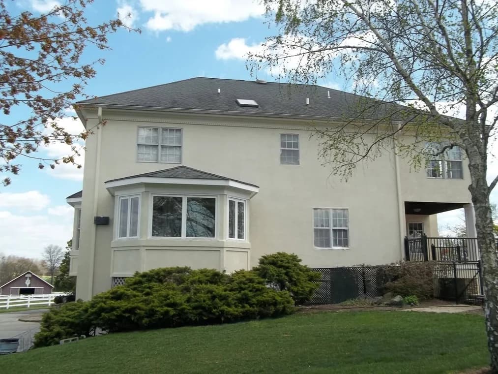 This is an image from Cherry Hill Painting in New Jersey. It highlights a large beige home with brown trim and a well-kept exterior finish.