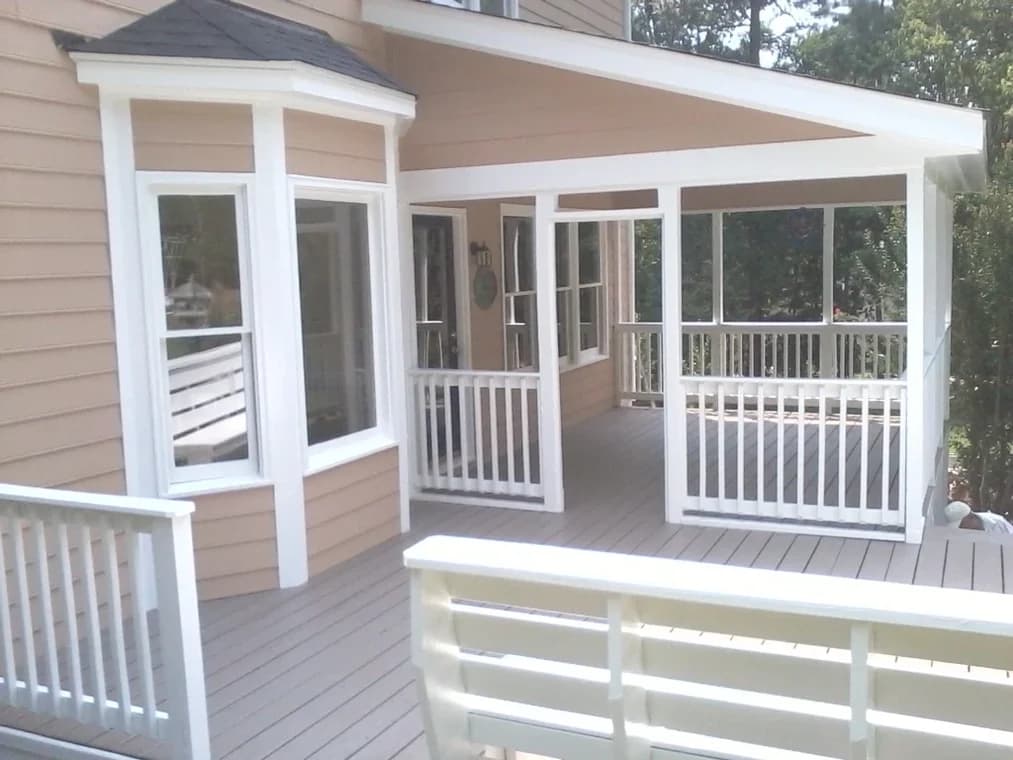 Deck painting project by Garcia's Painting & Repair NC, LLC in Chapel Hill, NC. The image shows tan siding, white railings, and a gray deck floor.