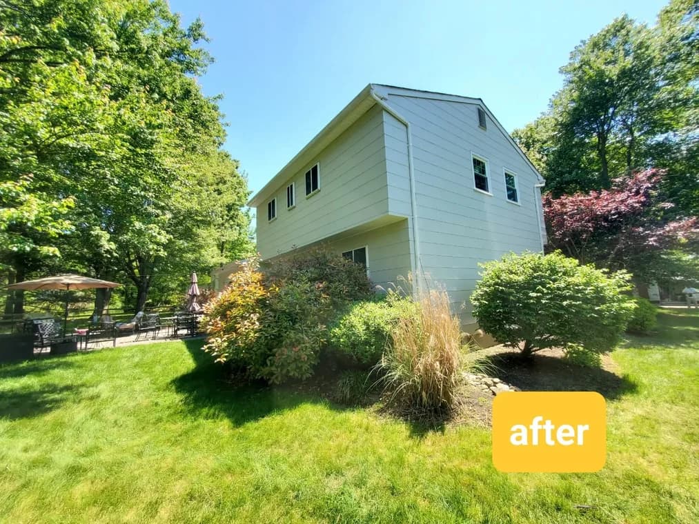 Side view of a two-story white house surrounded by green landscaping after exterior painting by Four Golden Brothers Painting.