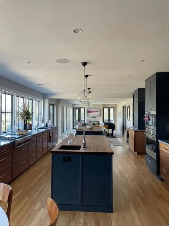 This is an image from Azul Painting Corp, located in New Jersey. The image shows a modern kitchen interior with painted cabinetry, a large island, hardwood floors, and recessed ceiling lighting.