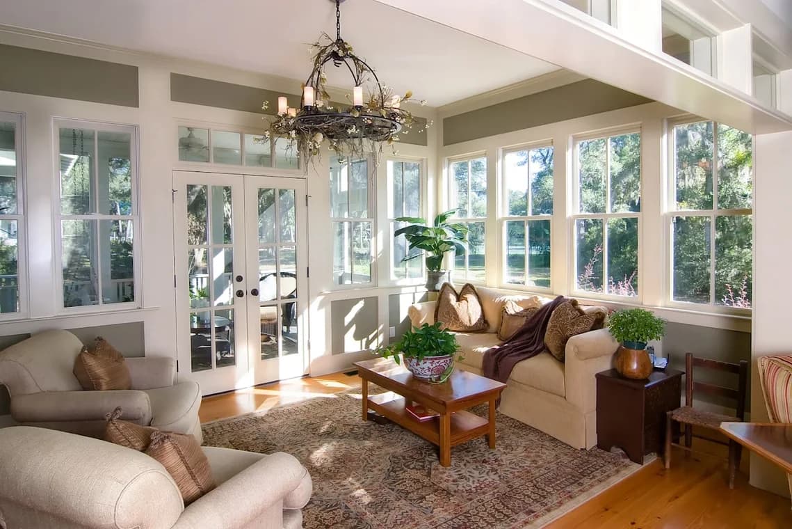 "This is an image from CertaPro Painters of NW San Antonio, located in Texas. The living room shows bright natural light, white-trimmed windows, neutral furniture, and a rustic chandelier above a patterned area rug."