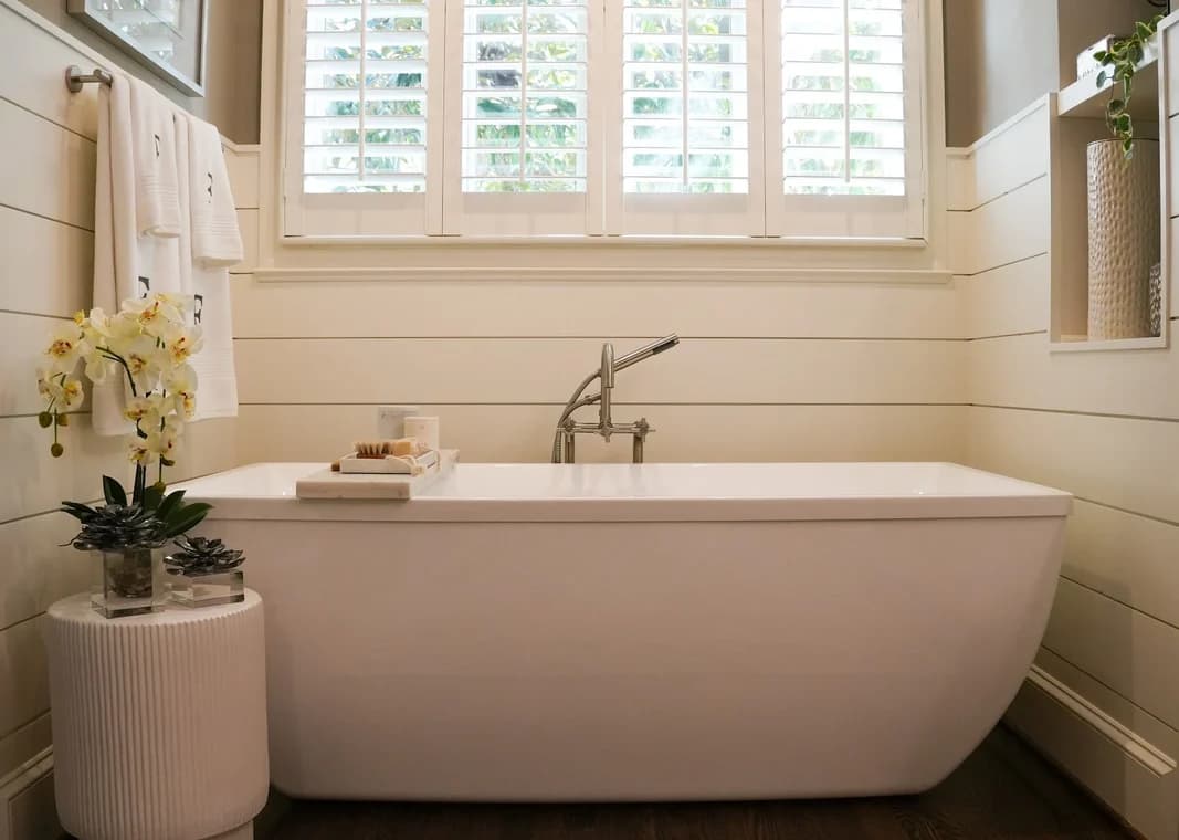 Interior painting project by Grace Painting & Contractors in Mooresville, NC. The image shows a bathroom with shiplap walls, white trim, shutters, and a freestanding tub.