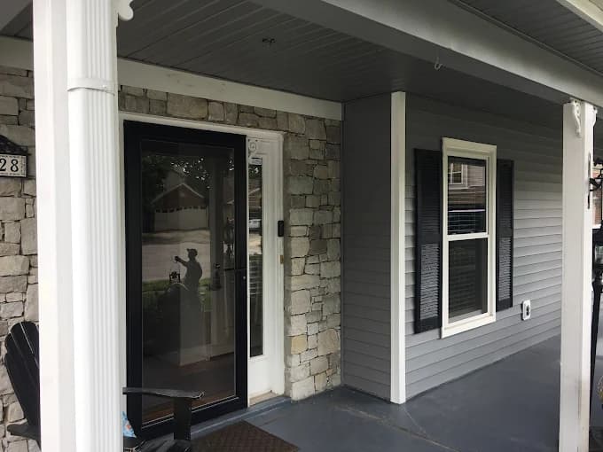 This is an image from Spray-Net Lexington, located in Kentucky. The image shows a freshly painted home exterior porch area with gray siding, stone accents, and crisp white trim.