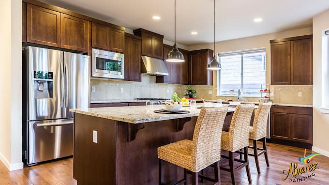 "This is an image from Alvarez Painting, located in Texas. The image shows a modern kitchen with dark wood cabinets, stainless steel appliances, and freshly painted walls."