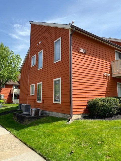 This is an image from Pizzazz Painting, showing the exterior of a red multi-unit residential building with several tall windows and a well-maintained grassy lawn.