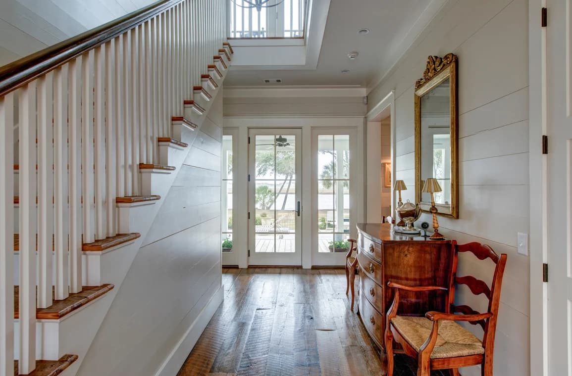 This is an image from Hands On Painters, located in Maryland. The interior hallway features wood flooring, a staircase with white railings, shiplap walls, and glass doors opening to a porch.