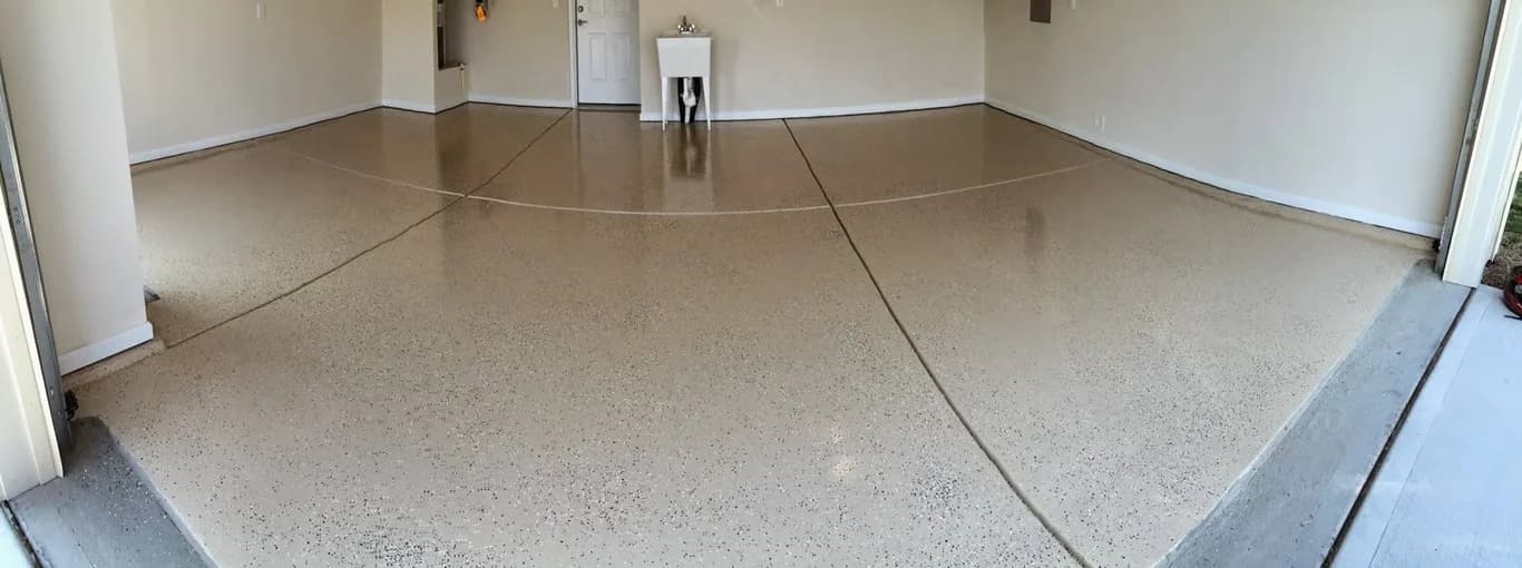 Garage floor coating project by Express Yourself Paint LLC in Raleigh, North Carolina. The image shows a tan speckled floor across a wide two-car garage.