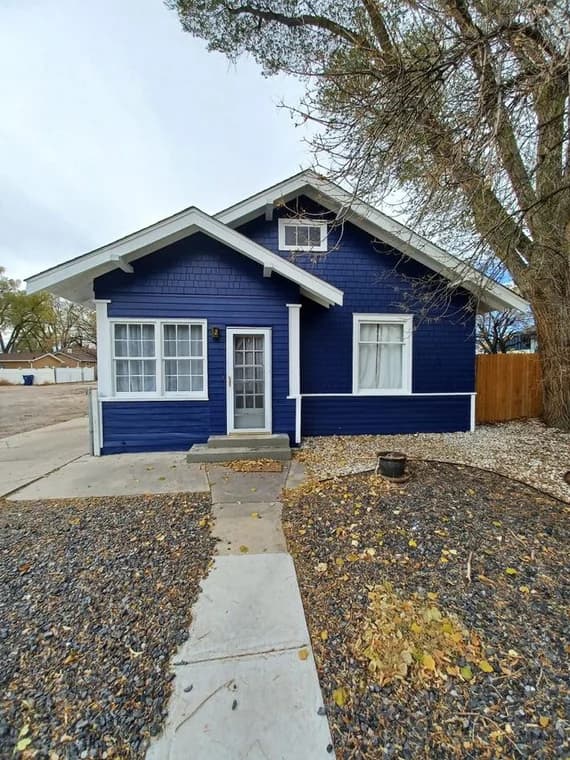 This is an image from All Painting Plus 2, LLC company, located in Colorado Springs, CO The image is a front view of a freshly painted navy blue house with white trim, completed by All Painting Plus 2 LLC exterior painting contractors.