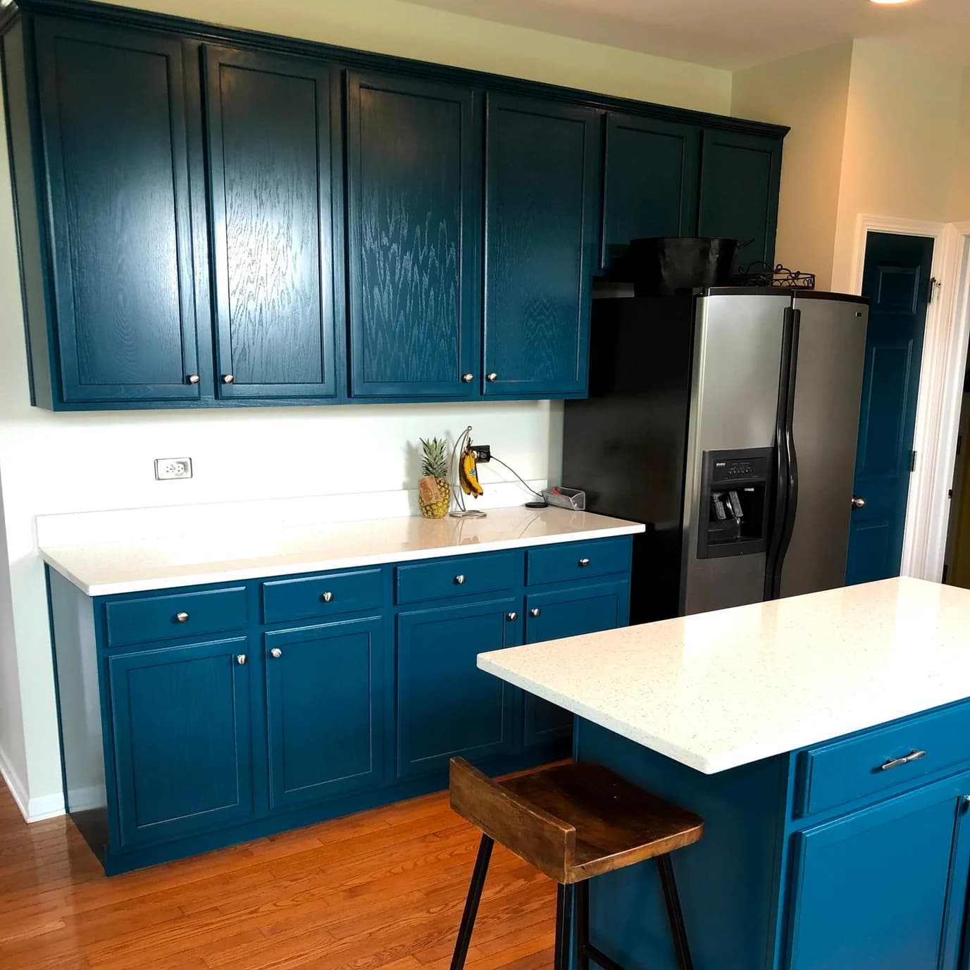 Cabinet painting by Tupelo Lane Designs in Naperville, Illinois. The image shows teal kitchen cabinets, white counters, and stainless appliances.