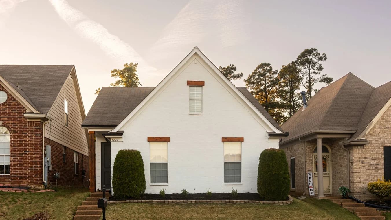 Exterior painting by Caldwell Painting Memphis in Cordova, Tennessee. The image shows a white brick home with dark trim and wood window accents.