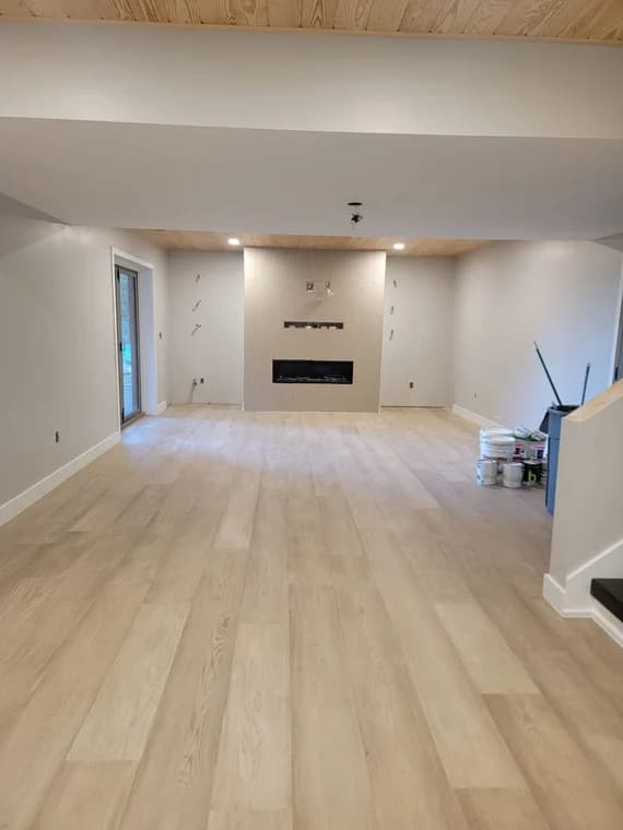 Interior painting project by JV Painting Services in Hendersonville, NC. The image shows an open room with pale walls, wood floors, and a fireplace.