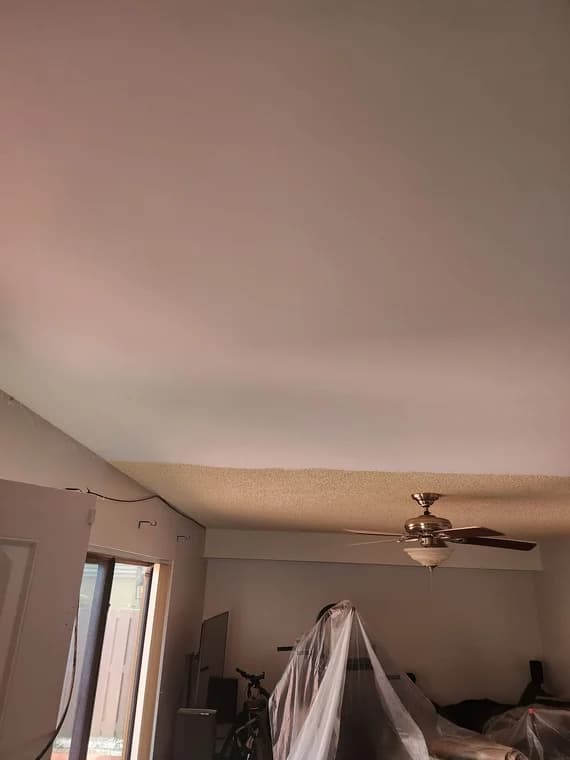 This is an image from Big Family Painting Co  company, located in Boca Raton, FL. The image is a living room ceiling before and after popcorn ceiling removal and skim coating, with furniture covered in plastic for protection