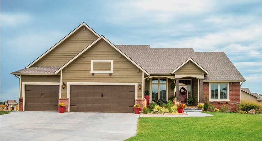 This is an image from CertaPro Painters of Wichita East KS. The image is a large tan ranch-style home in Wichita KS with new exterior paint and brick accents.