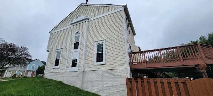 This is an image from Seven Oaks Painting Services, located in Ohio. The photo shows a beige two-story home exterior with white trim and a raised wooden deck on the side.