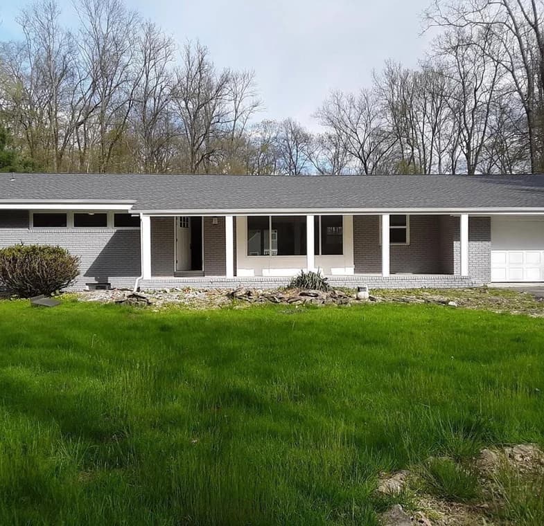 Exterior of a single-story brick home with fresh gray paint and white trim, completed by Romeo Painting Plus, LLC.
