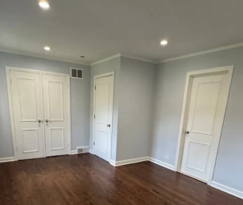 Interior painting project by Standard 28 in Deerfield, Illinois. The image shows a room with light gray walls, white doors and trim, recessed lights, and dark floors.