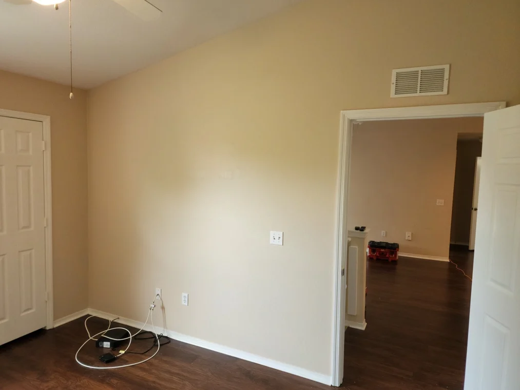 This is an image from Frank Fast Painter company, located in Panama City Beach, FL. The image is a freshly painted beige interior wall with clean white baseboards and doors in home renovation project