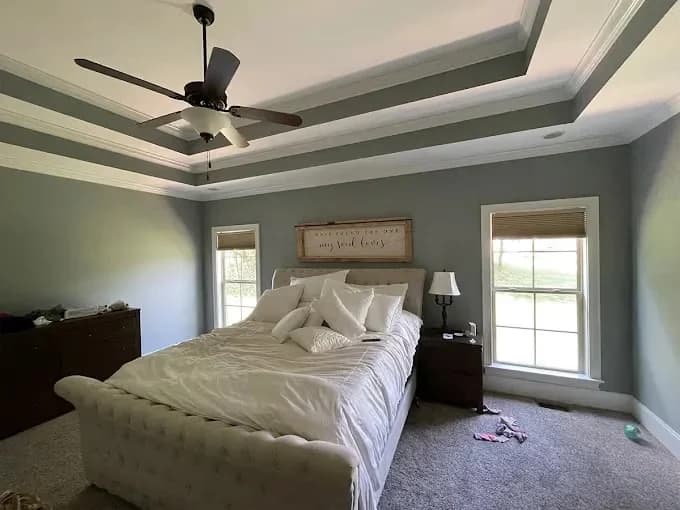 Painting project by New Direction Painting in Franklin, Tennessee. The image shows a green bedroom with a tray ceiling.