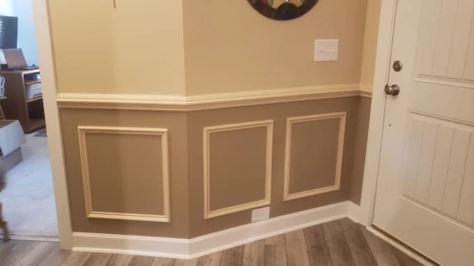 Interior trim painting project by R3 Painting in Hampstead, NC. The image shows wainscoting panels, beige walls, white doors, and wood floor.