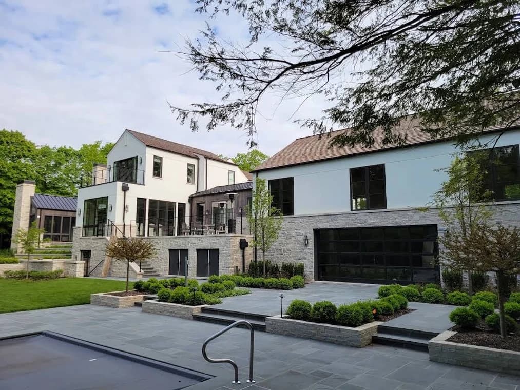 Exterior stucco project by JJ Stucco & Plastering System Inc. in Lake in the Hills, Illinois. The image shows a white modern home beside a pool and landscaped patio.