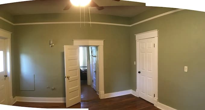 This is an image from Knight's Painting, located in New Mexico. The photo shows a freshly painted interior room with sage green walls, white trim, and wooden floors, highlighting a clean and professional finish.