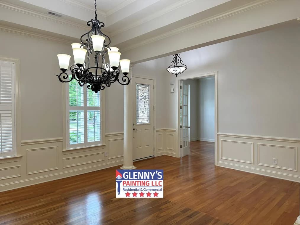 Interior painting project by Glenny's Painting LLC in Charlotte, NC. The image shows beige walls, white wainscoting, hardwood floors, and chandeliers.