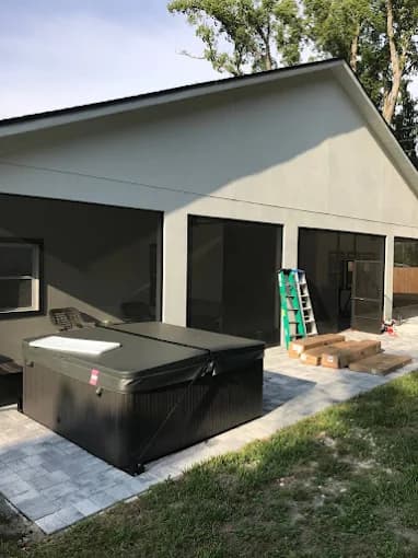 This is an image from Golden Hands Handymans company, located in Windermere, FL. The image is a covered patio construction with installed paver flooring, hot tub setup, and screened enclosures in a residential backyard