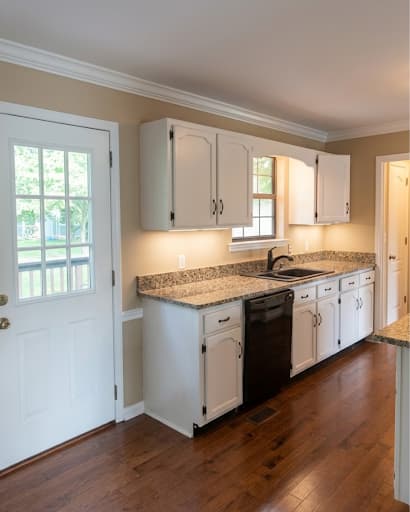 Painting work by Scott Brown Professional Painting & Remodeling in Chattanooga, Tennessee. The image shows a white kitchen with wood flooring.