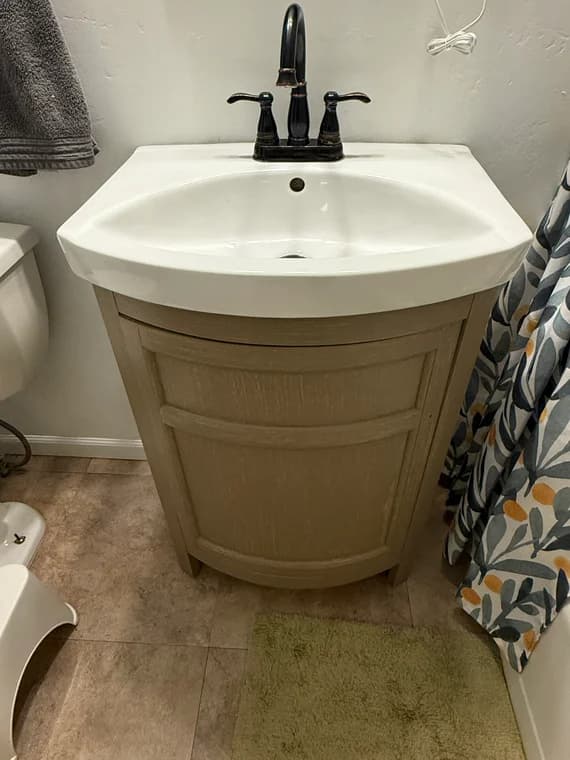 Installed light gray bathroom vanity with a white ceramic sink and modern black faucet.