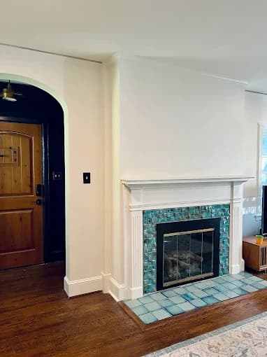Interior painting project by Pro Painting & Drywall LLC in East Flat Rock, NC. The image shows a fireplace wall with white trim, pale walls, and wood floors.