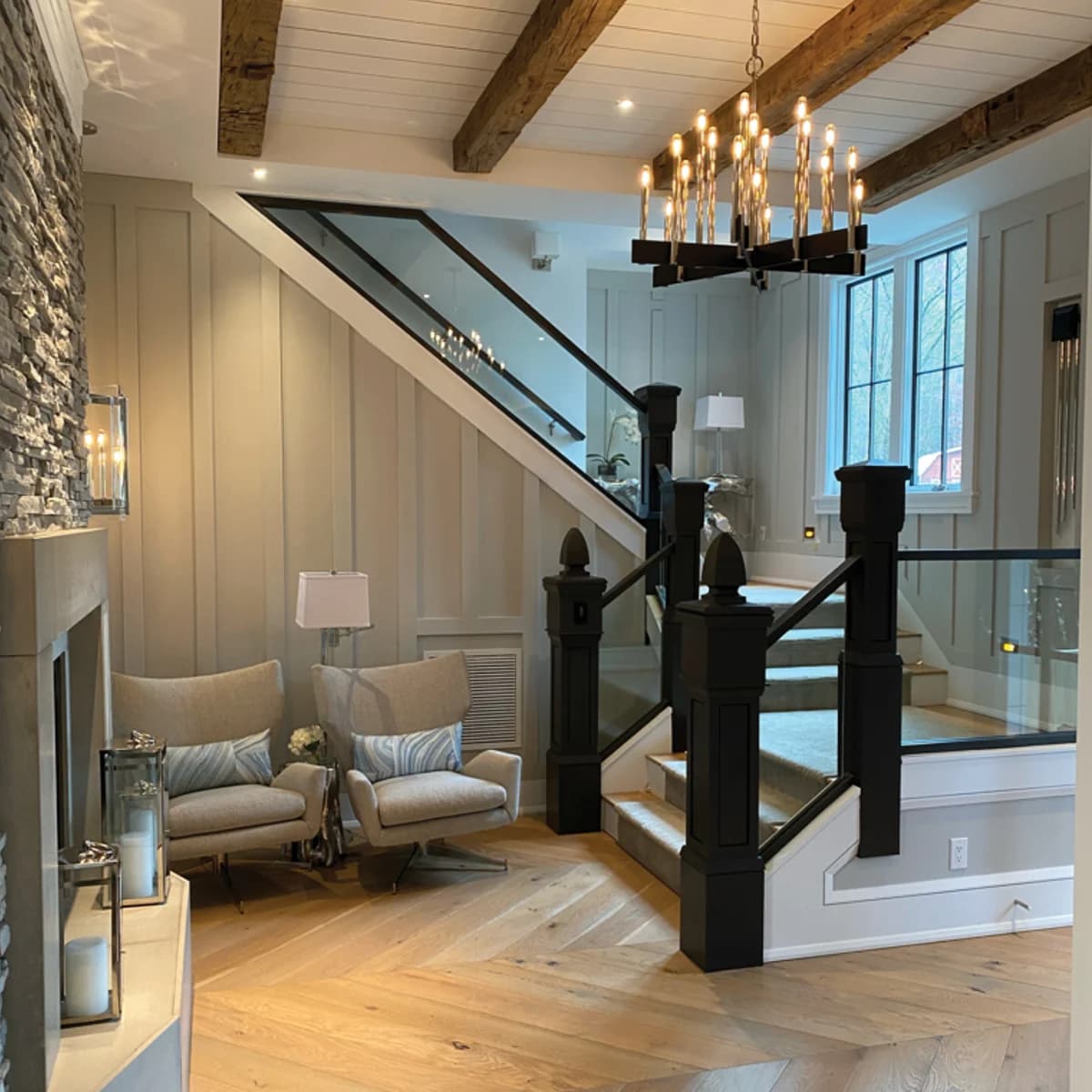 Interior painting project by Burlett Painting, LLC in Hendersonville, North Carolina. The image shows neutral walls, wood beams, a chandelier, and glass railings.